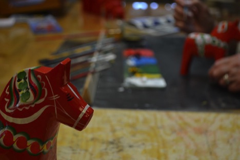Dala horse with paints in background